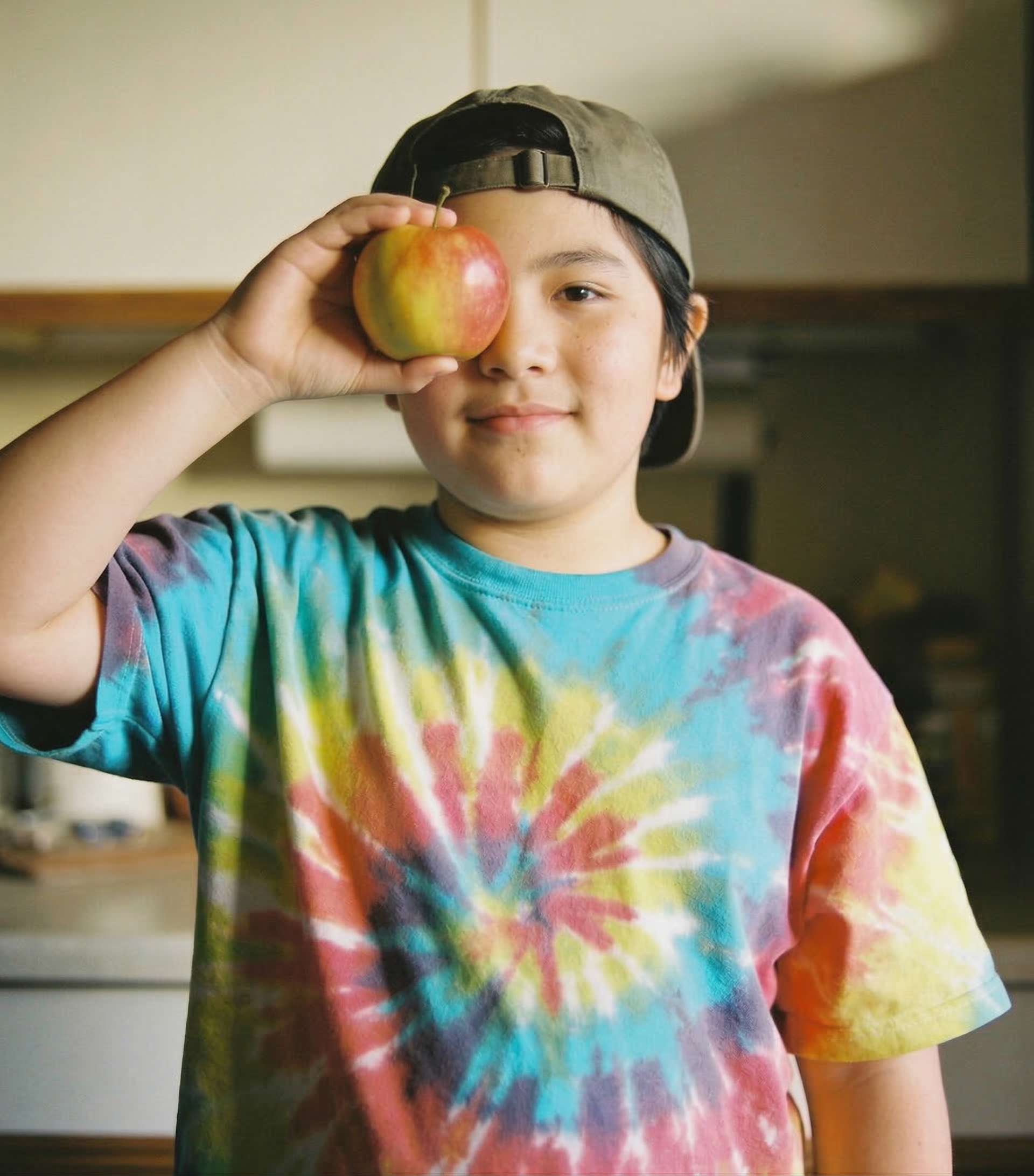 A smiling boy holding a fresh apple outdoors