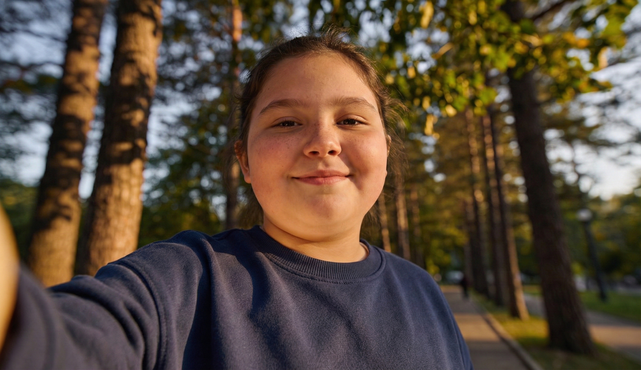 Smiling girl taking a selfie outdoors in a forest